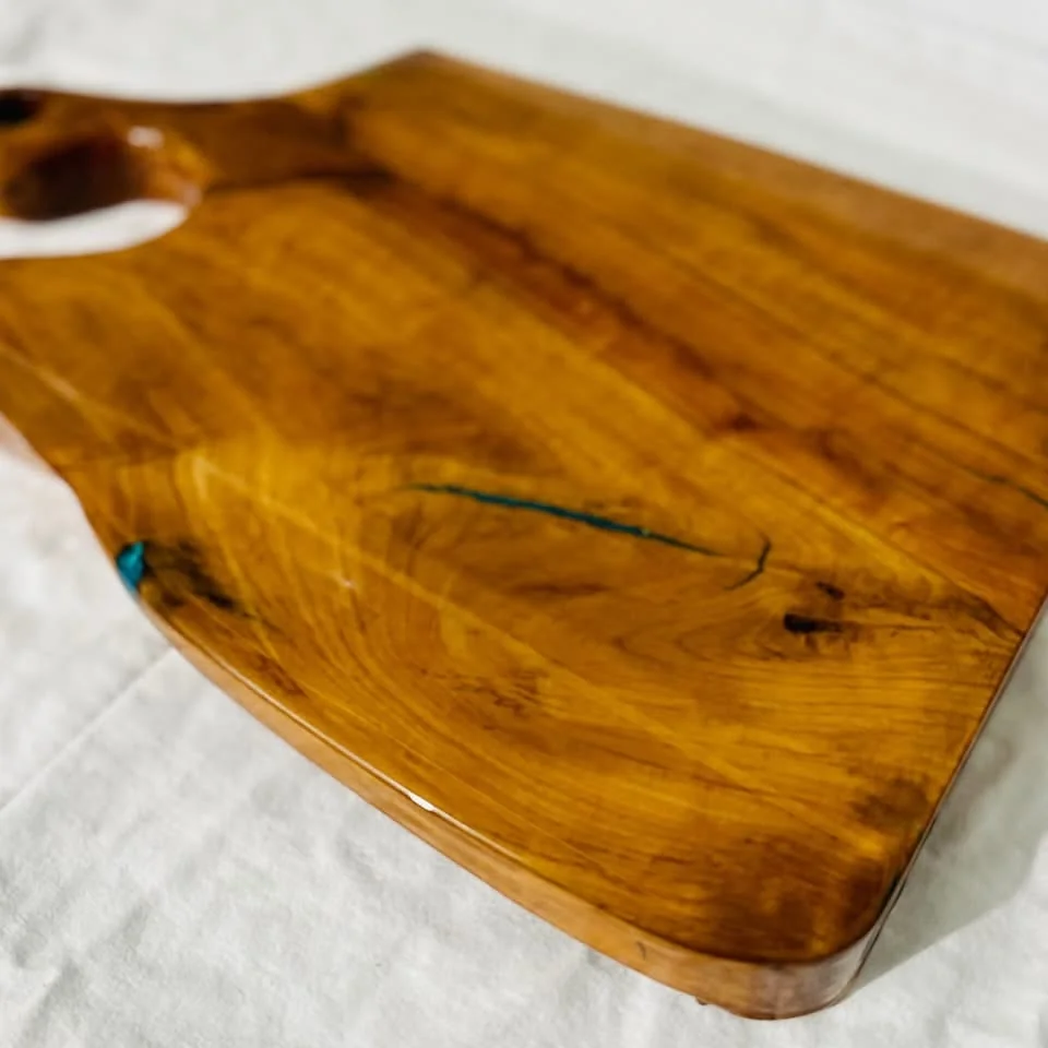 Close view of a rounded wood board edge with turquoise epoxy infill