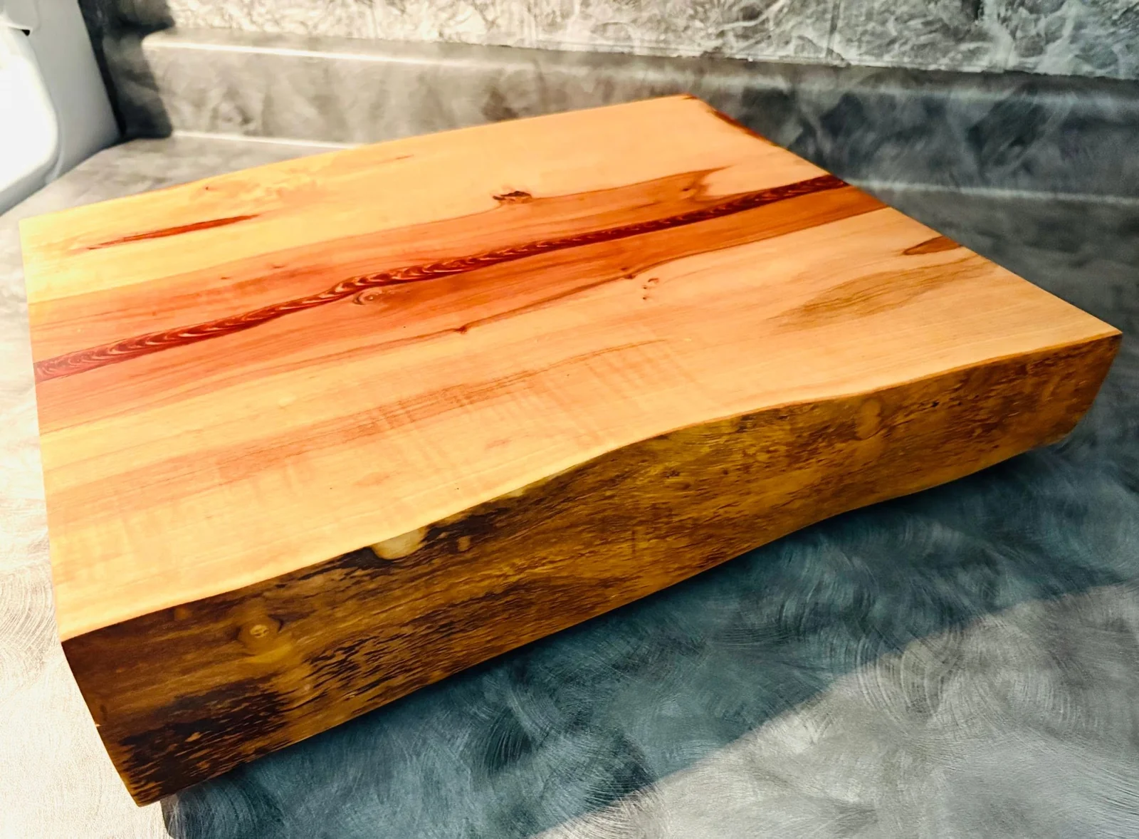 Thick rectangular wood board with a natural live edge and narrow resin detail
