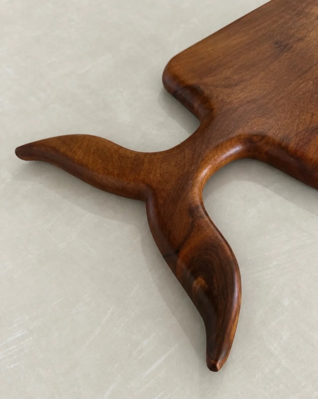Detail of the whale-tail serving board handle, not a coaster